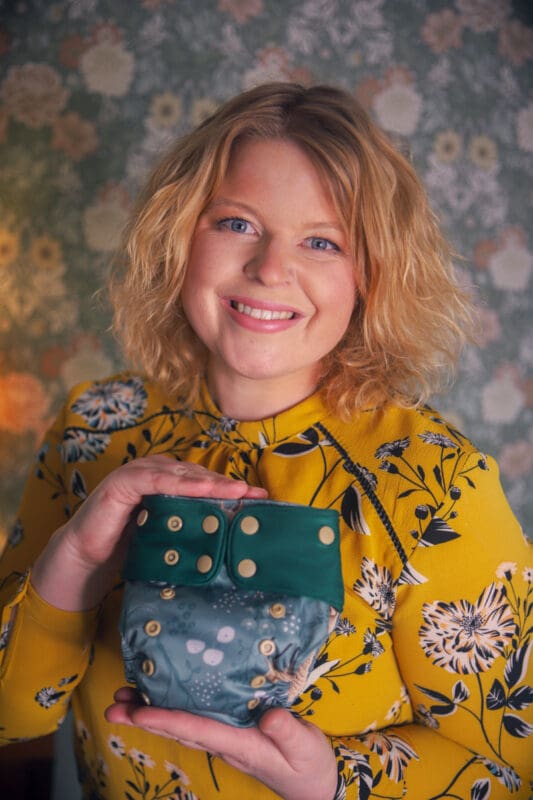 leende kvinna i gul blus som håller i en tygblöja